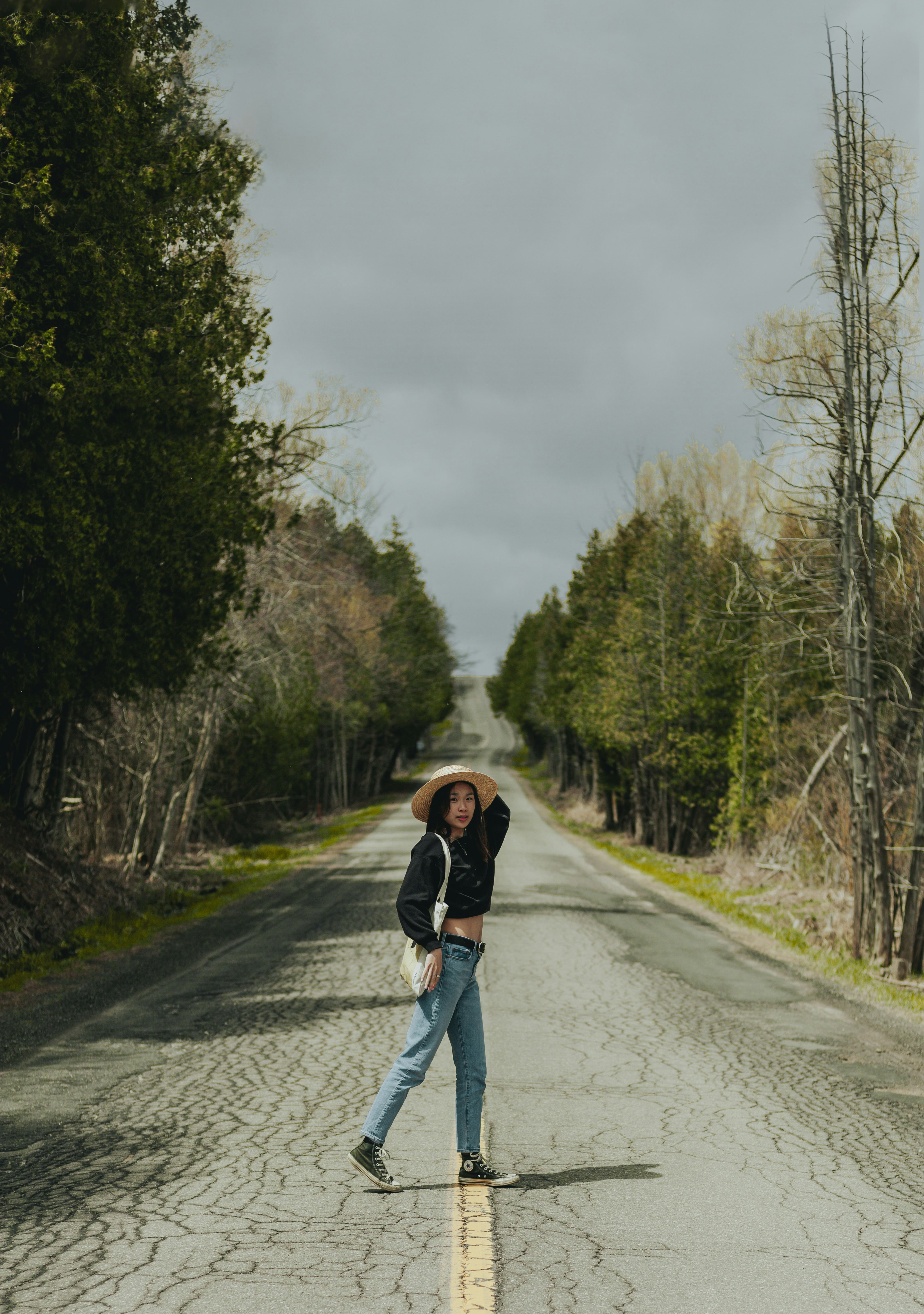 woman in black jacket and black pants standing on gray asphalt road during daytime
